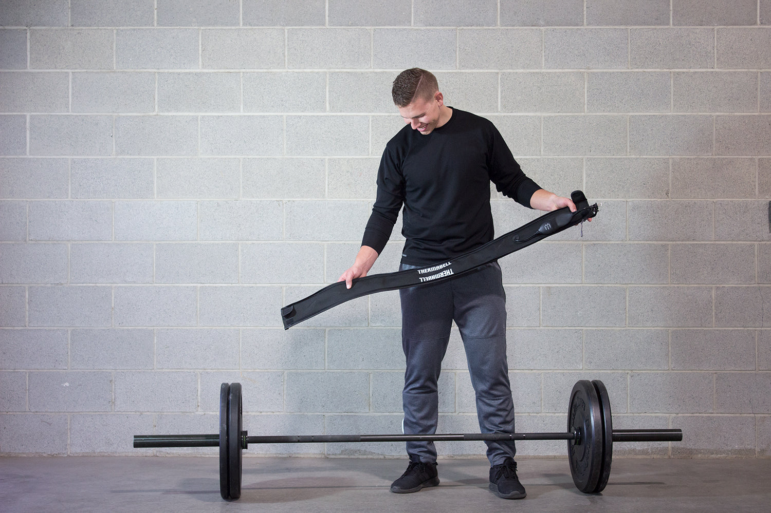 Barbell warmer held by weightlifter in cold garage gym